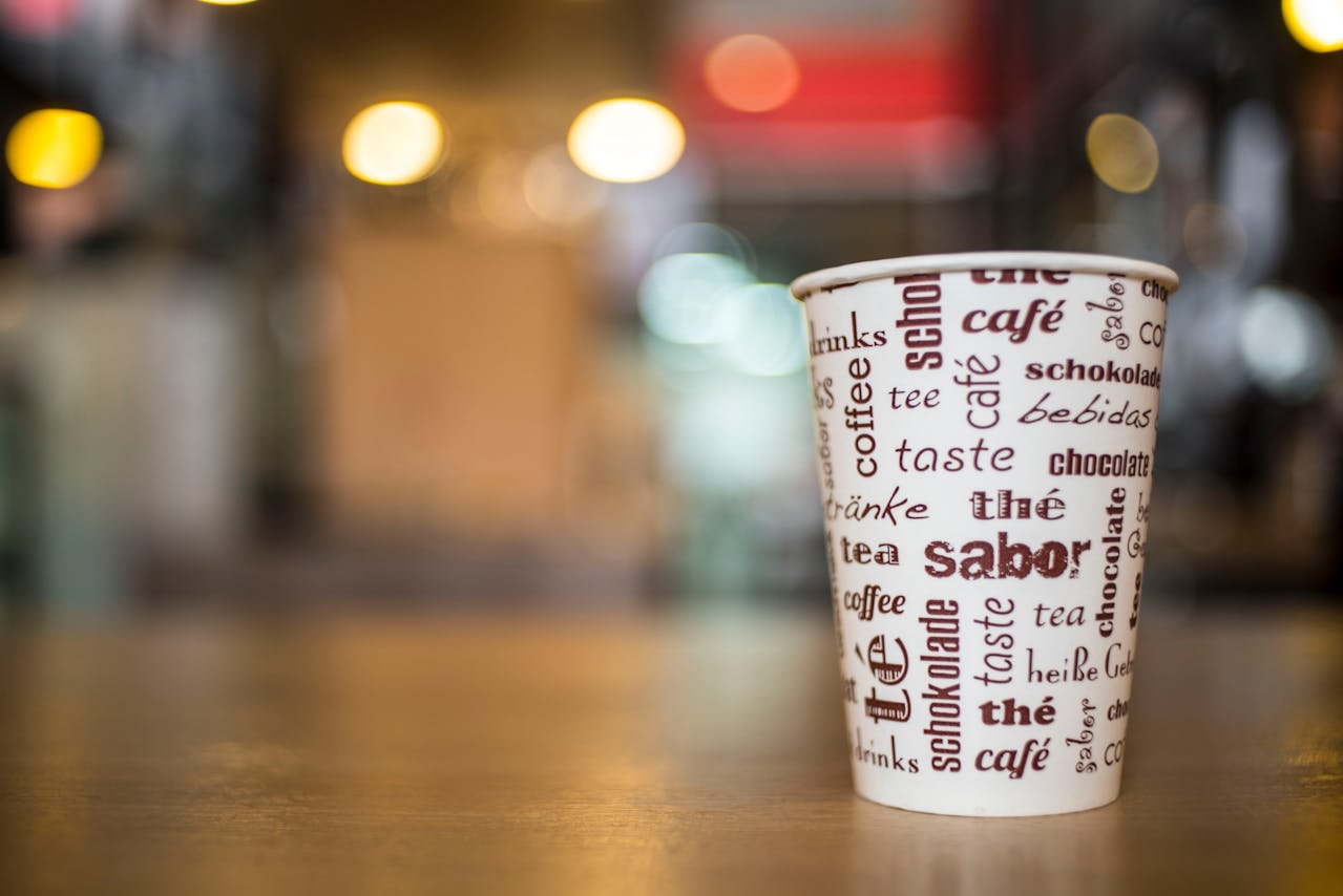 Café en un vaso de carton puesto en un mostrador