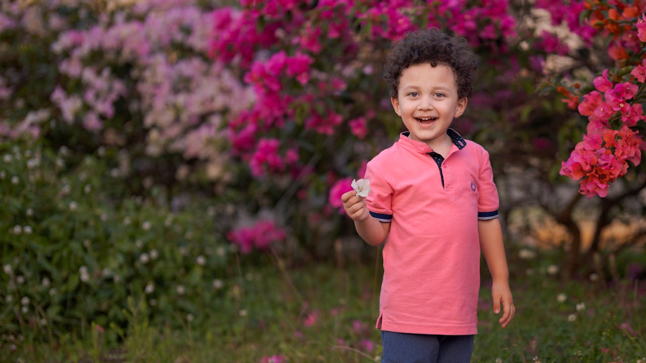 Niño jugando en un parque con una flor morada